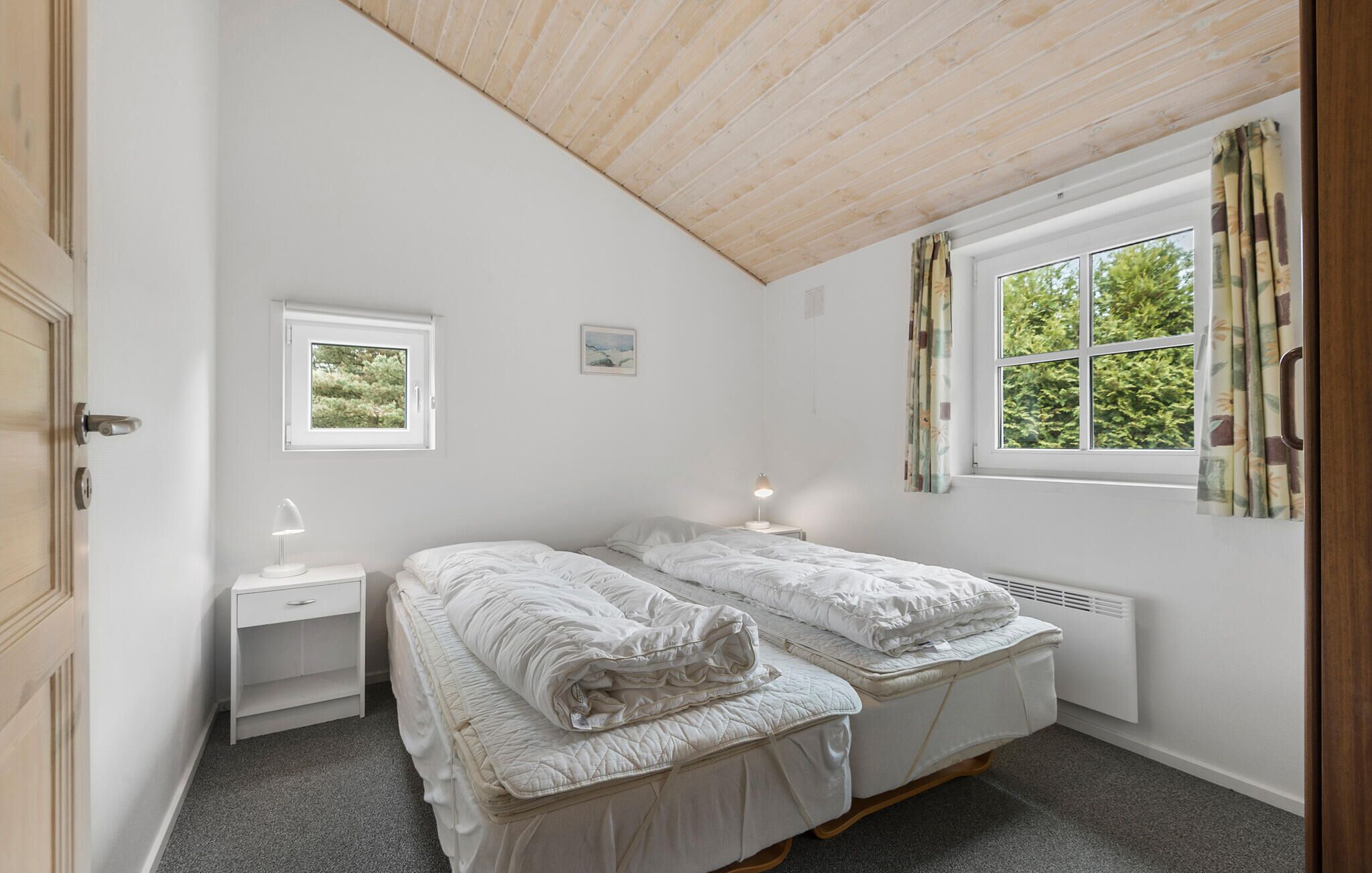 Une chambre avec deux lits, une fenêtre, une table de chevet et un radiateur.