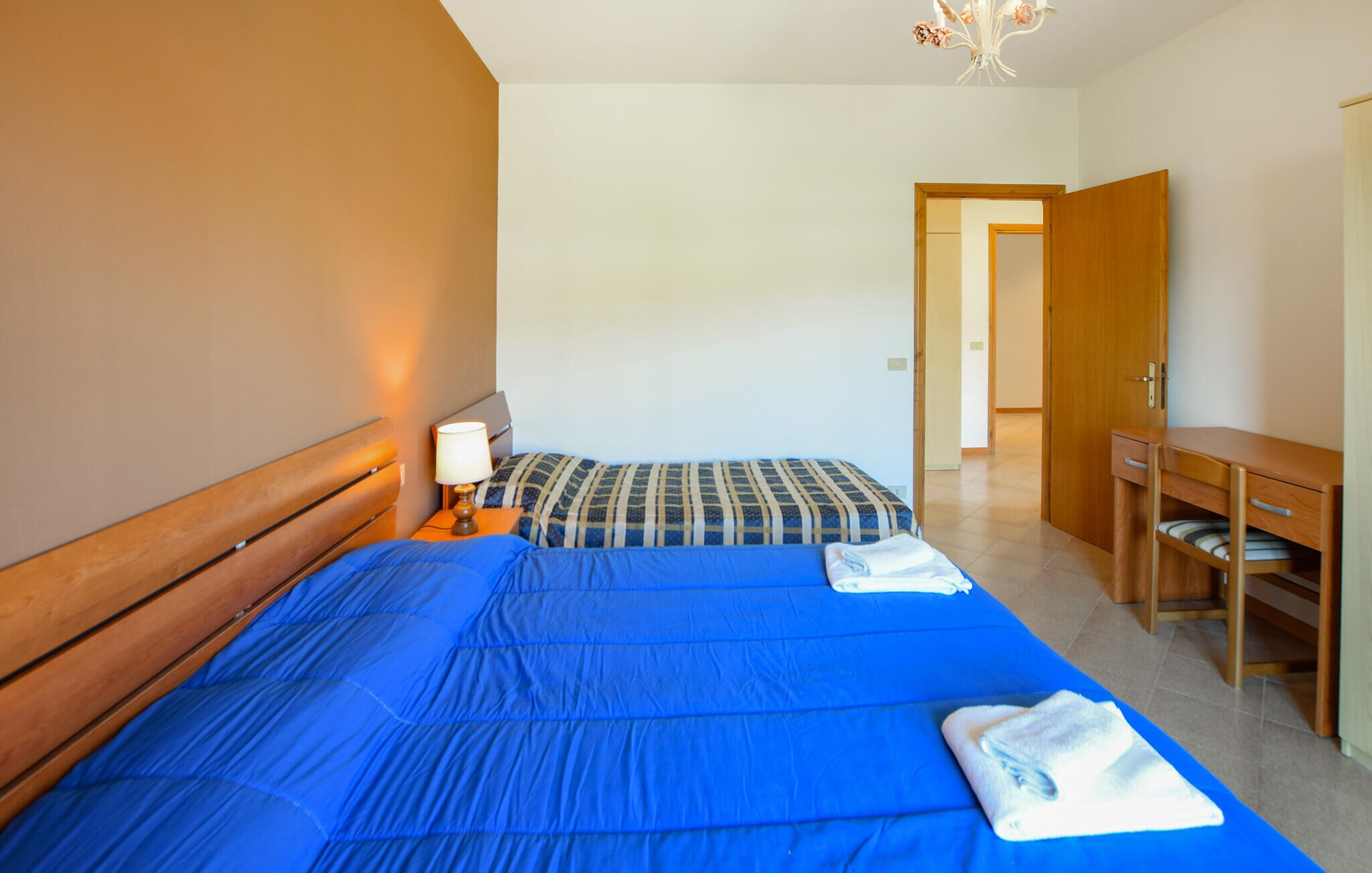 Un dormitorio con cama, mesita de noche, escritorio y silla.
