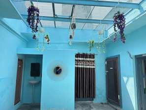 A room with a skylight, hanging plants, a sink, and a door labeled 'KITCHEN'.