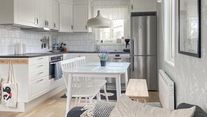 A modern kitchen with white cabinetry, a stainless steel refrigerator, and a dining area with a table and chairs. - Stunning home in Gotland with kitchen (Gotland)