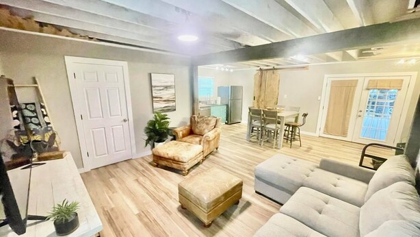A spacious living room with a sofa, armchair, and ottoman, a dining area with a table and chairs, and a kitchen in the background. - The Eclectic - "treehouse" - B (Bryan)