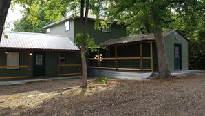 A two-story building with a green exterior and a metal roof, surrounded by trees. - The Eclectic - "treehouse" - B (Bryan)