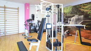 A gym with various exercise equipment, a treadmill, and a wall-mounted TV.