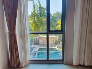 A room with a large window overlooking a swimming pool and a building with a balcony. - Ana Park Chiangmai (Chiang Mai)