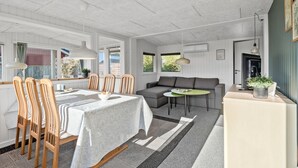 Een moderne woonkamer met een eethoek, met een bank, een klein tafeltje en een eettafel met stoelen.