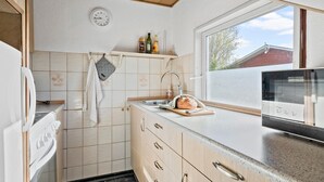 Een keuken met een raam, een klok en een aanrecht met een brood.