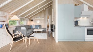 A modern, open-plan living area with a sofa, chairs, a dining table, and a kitchen with cabinets and appliances. - Lovely home in Middelfart with kitchen (Middelfart)
