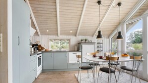 A modern kitchen with light blue cabinets, a central island, and pendant lighting. - Lovely home in Middelfart with kitchen (Middelfart)