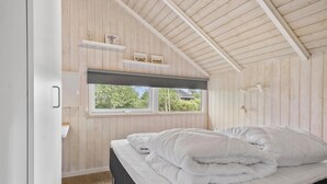 A bedroom with a bed, wooden walls, a window, and a ceiling fan. - Lovely home in Middelfart with kitchen (Middelfart)