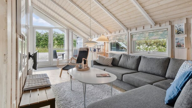 A modern interior with a grey sofa, a small round table, and a wicker chair. - Lovely home in Middelfart with kitchen (Middelfart)