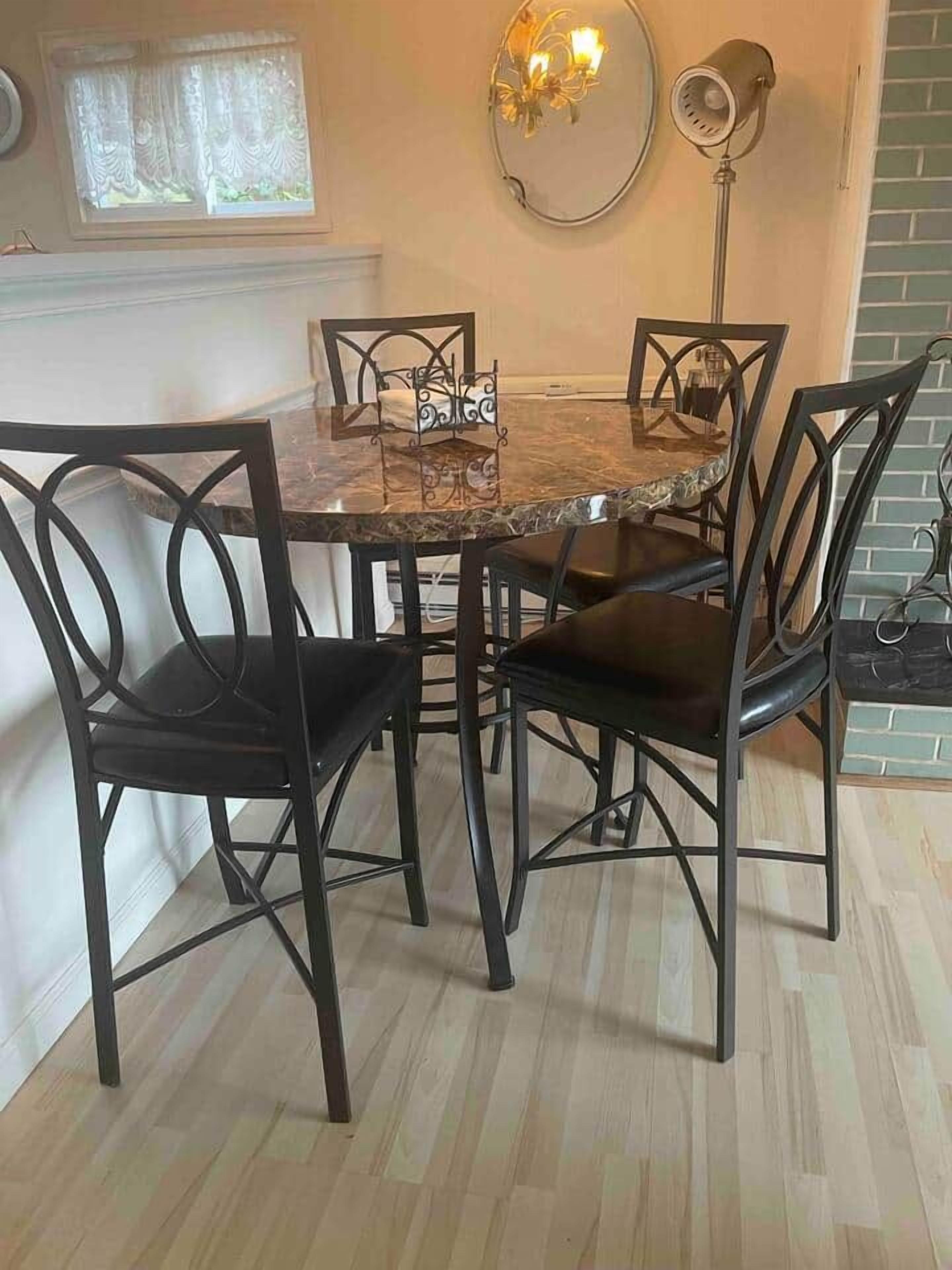 A dining area with a marble table, black chairs, a floor lamp, and a window with curtains.