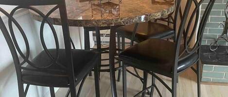 Un comedor con una mesa de mármol, sillas negras, una lámpara de pie y una ventana con cortinas.