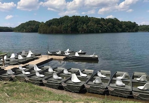 Un muelle a orillas del lago con varias lanchas y una pasarela de madera.