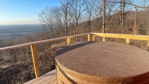 Eine Holzterrasse mit Whirlpool, einem gemusterten Teppich und Blick auf die Landschaft.