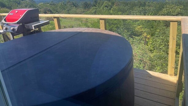 A deck with a round table and a grill, overlooking a hilly landscape. - Beau Ridge Cabin (Little Cabin with a big view) (Linden)