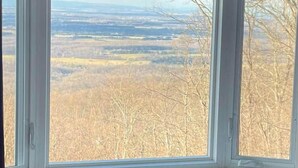 Ein Zimmer mit einem großen Fenster und Blick auf eine bewaldete Landschaft.
