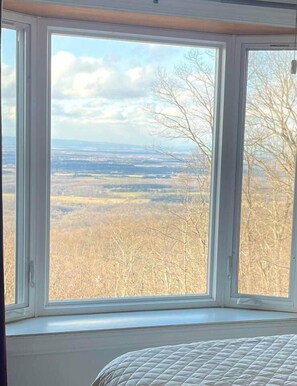 A room with a large window offering a view of a forested landscape.
