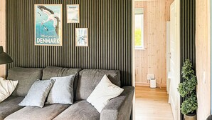 Ein modernes Wohnzimmer mit einem grauen Sofa, einem gerahmten Vogelposter und einem kleinen Blumentopf.