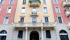 A multi-story building with a central entrance, balconies with plants, and a sign for 'Sartoria Stella Riparazione'. - Giovio Duplex Apartment (Milano)