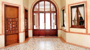 A hallway with a tiled floor, wooden doors, and windows with curtains. - Giovio Duplex Apartment (Milano)