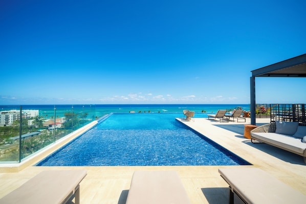 A clear blue sky, a swimming pool, and a view of the ocean.