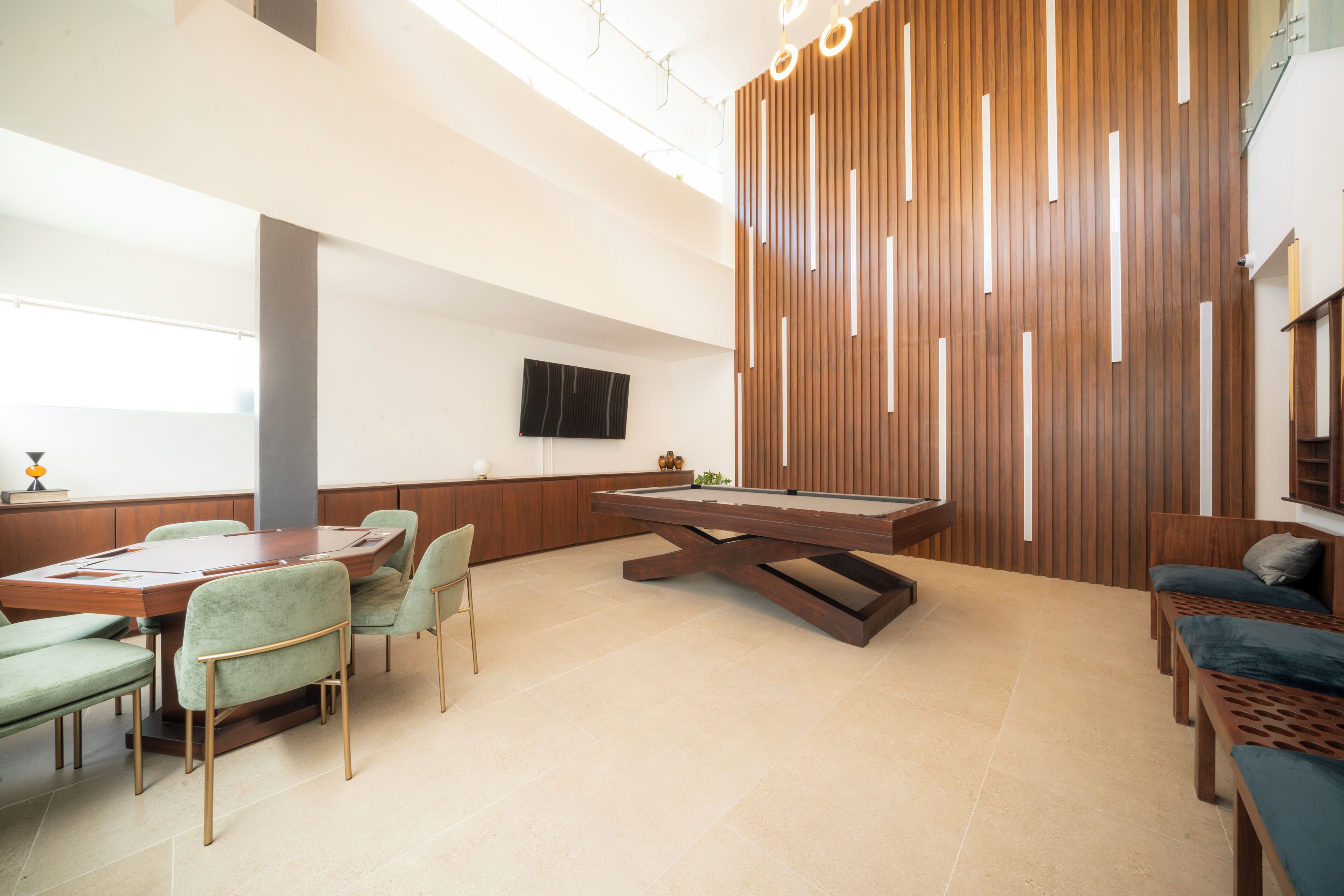 A modern lounge area with a pool table, comfortable seating, and a wooden accent wall.