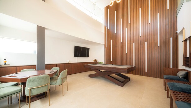 Un área de descanso moderna con mesa de billar, asientos cómodos y una pared de madera decorativa.