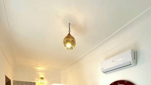Un couloir avec une porte en bois, un miroir et un climatiseur fixé au mur.