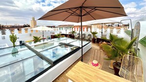 Une terrasse sur le toit dotée d’un plancher en verre, de sièges extérieurs et de parasols.
