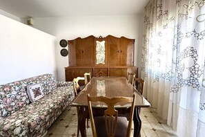 Een eethoek met een houten tafel en stoelen, een bloemenbank en een decoratiemakelaar.