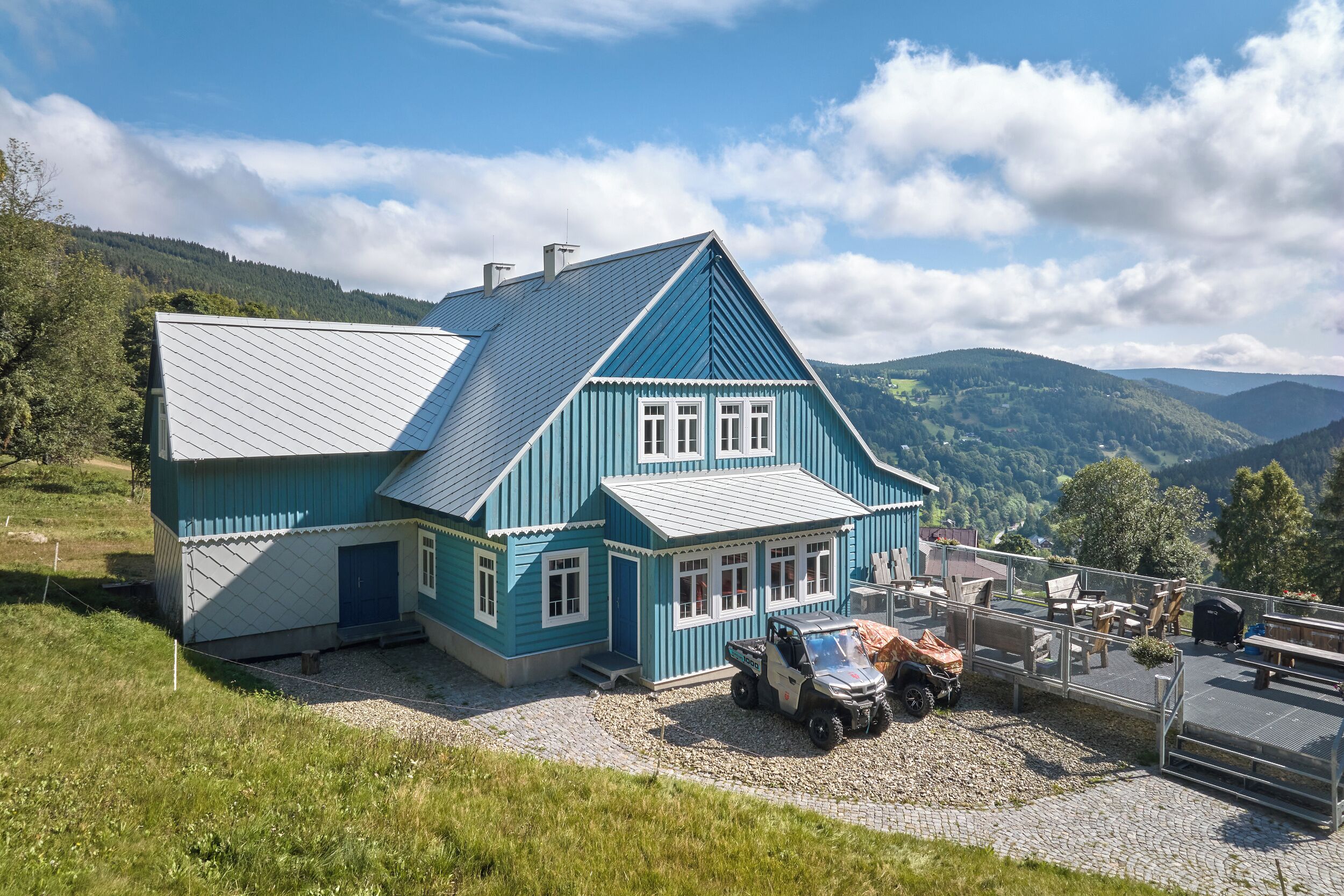 Ein blaues Haus mit geneigtem Dach, einer Schotterauffahrt und einem abgestellten Quad.