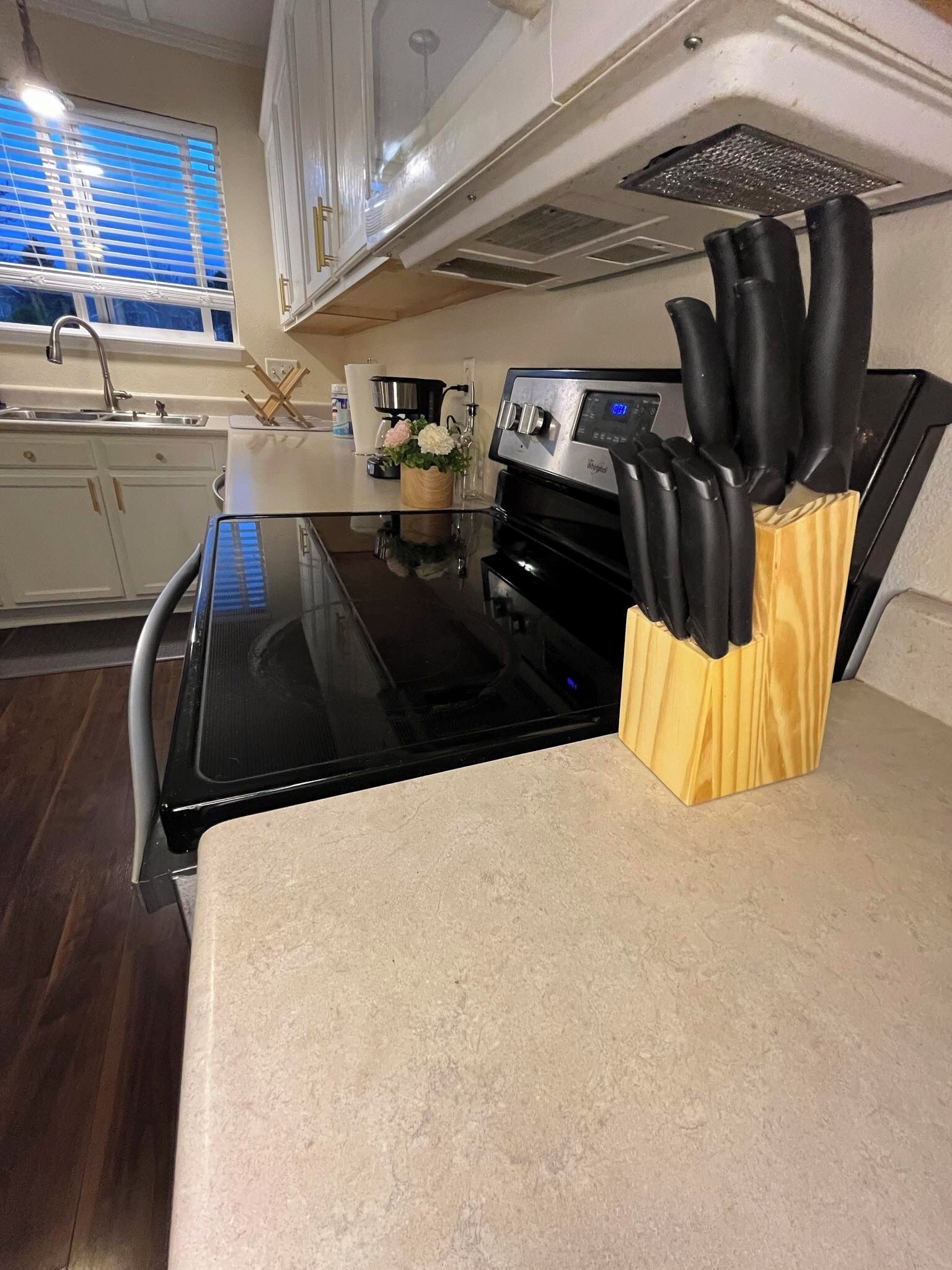 A kitchen with a black stove, a sink, and a wooden knife block on the counter.