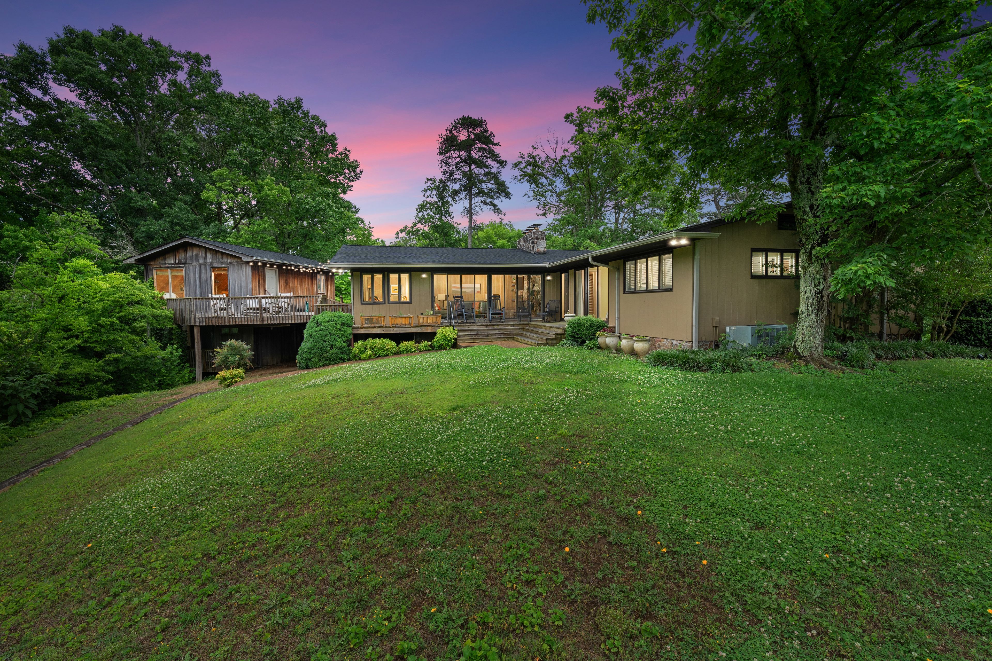 A two-story house with a deck, surrounded by a well-maintained lawn and trees.
