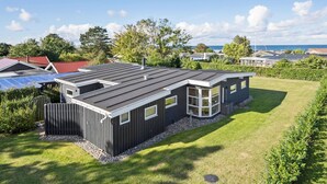 Ein modernes Haus mit Satteldach, großen Fenstern und einem gepflegten Rasen.