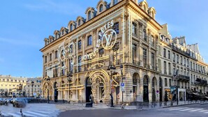 A historic building with ornate architecture, large windows, and a prominent Louis Vuitton store.
