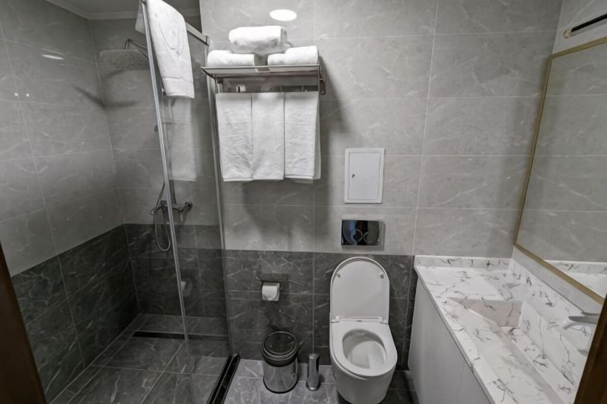 Kylpyhuone, jossa on suihku, wc ja pyyheteline pyyhkeineen.