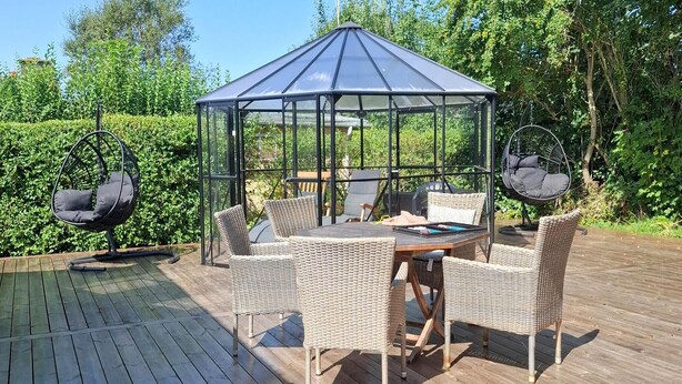 Un espace extérieur aménagé, abrité et doté de meubles en osier, ainsi qu’un belvédère en verre.