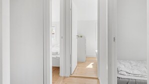 Un couloir étroit mène à une chambre qui contient un lit et une petite table.