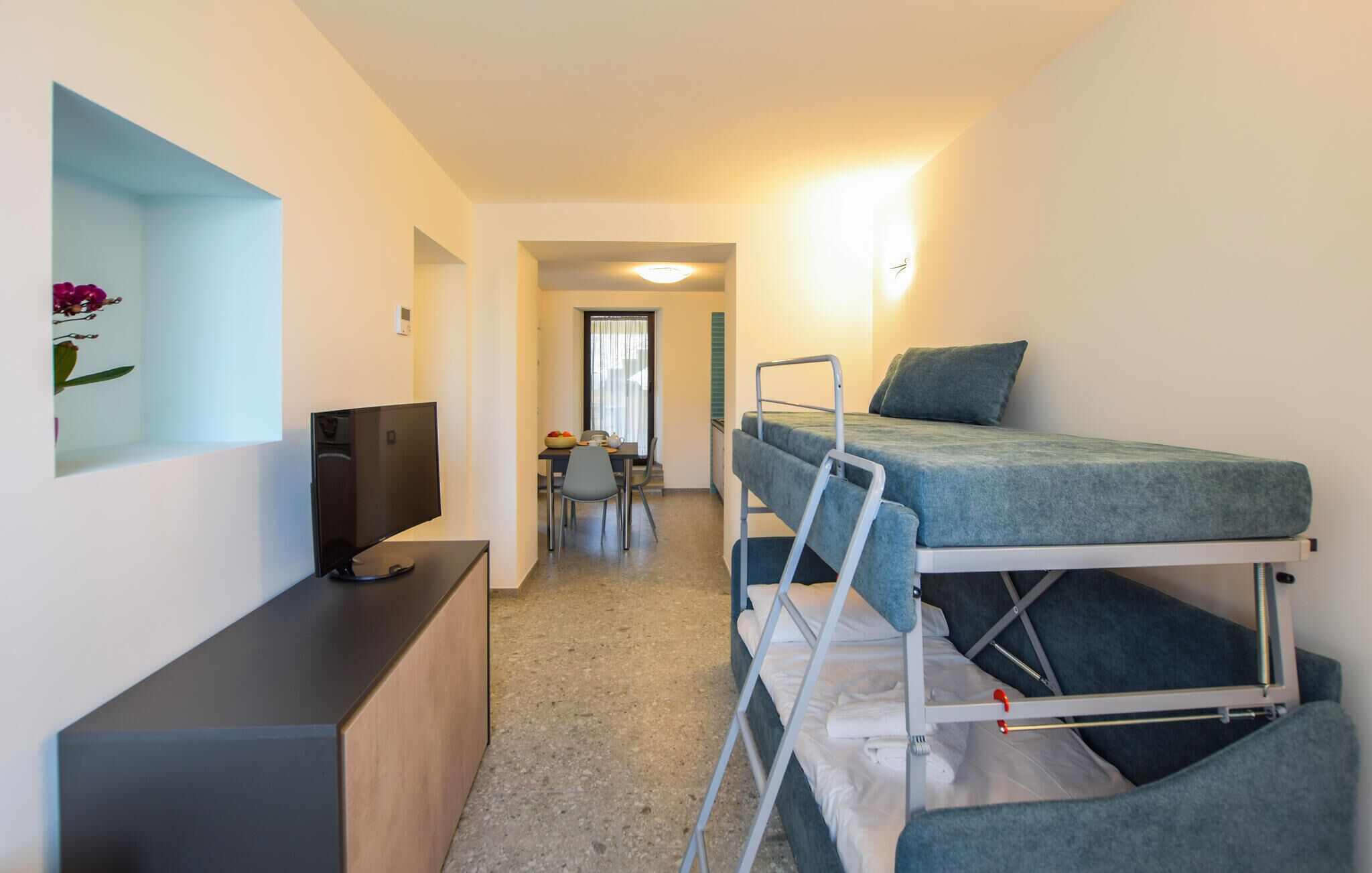 A compact room with a bunk bed, a desk with a computer, and a small dining area.