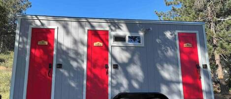 A small, single-story mobile home with three red doors and a small window.