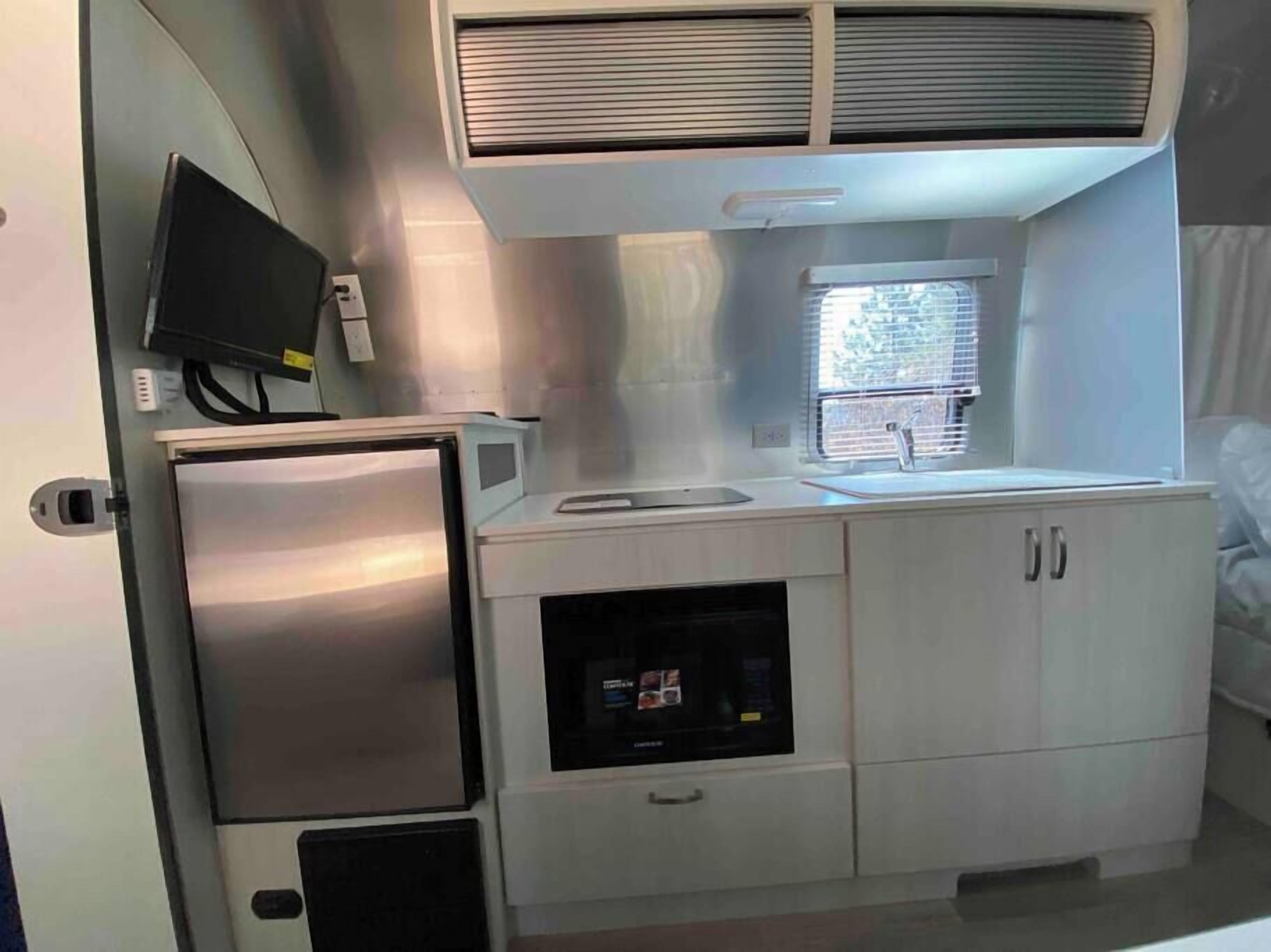 A compact kitchenette with a refrigerator, microwave, and sink.
