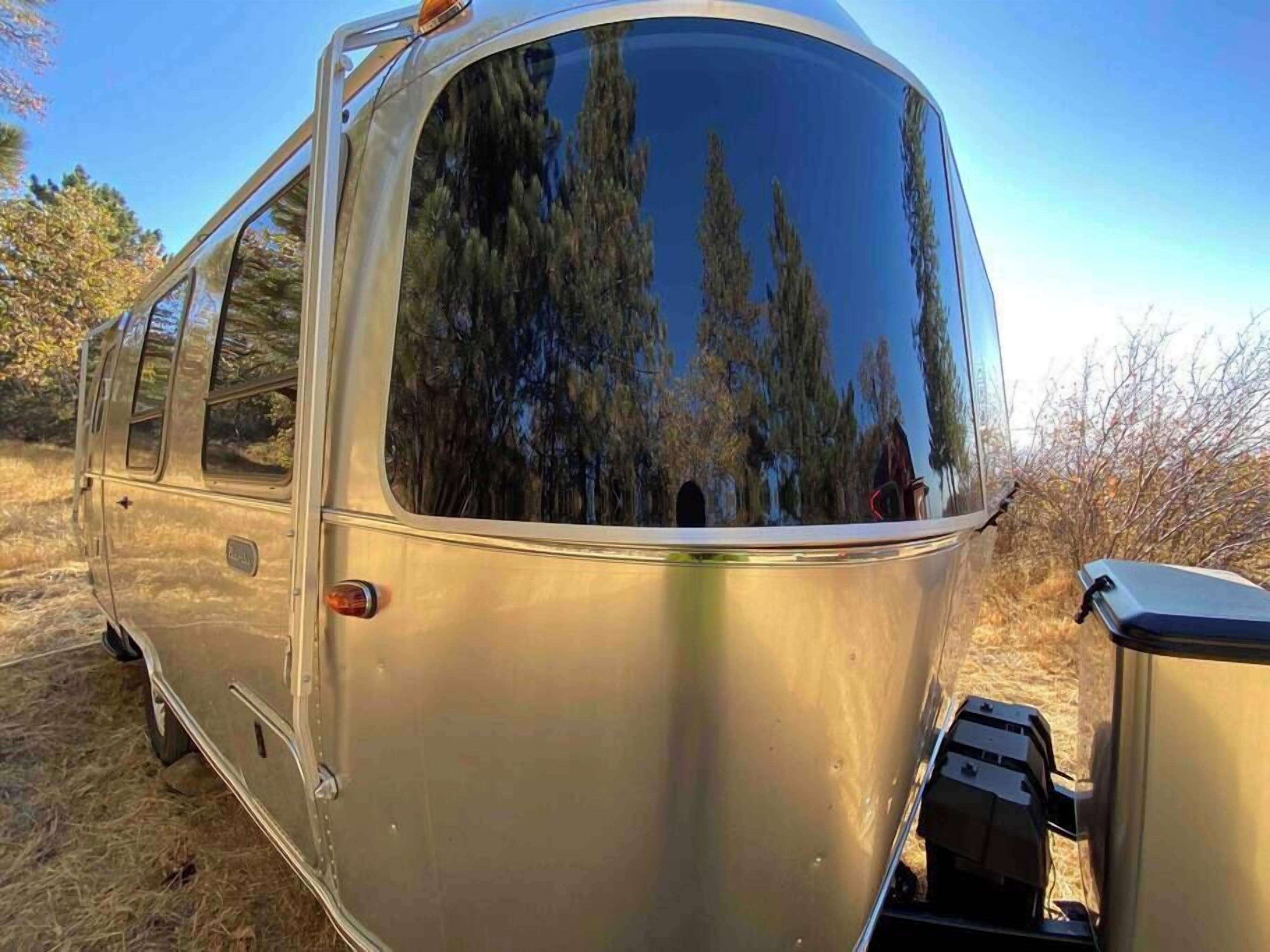 A vintage camper van parked in a natural setting with a clear view of trees through the windows.