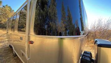 A vintage camper van parked in a natural setting with a clear view of trees through the windows.