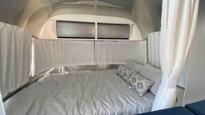A compact, well-lit sleeping area with a bed, a pillow, and a headboard. - Airstream - 15 Minutes to Kings Canyon (Dunlap)