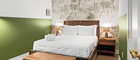 Una cama bien hecha con sábanas blancas, un cabecero de madera y dos lámparas de noche.