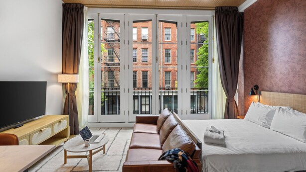 Une chambre d’hôtel avec un grand lit, un canapé, un bureau avec un ordinateur portable et une télévision.