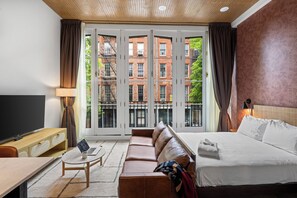 Une chambre d’hôtel avec un grand lit, un canapé, un bureau avec un ordinateur portable et une télévision.
