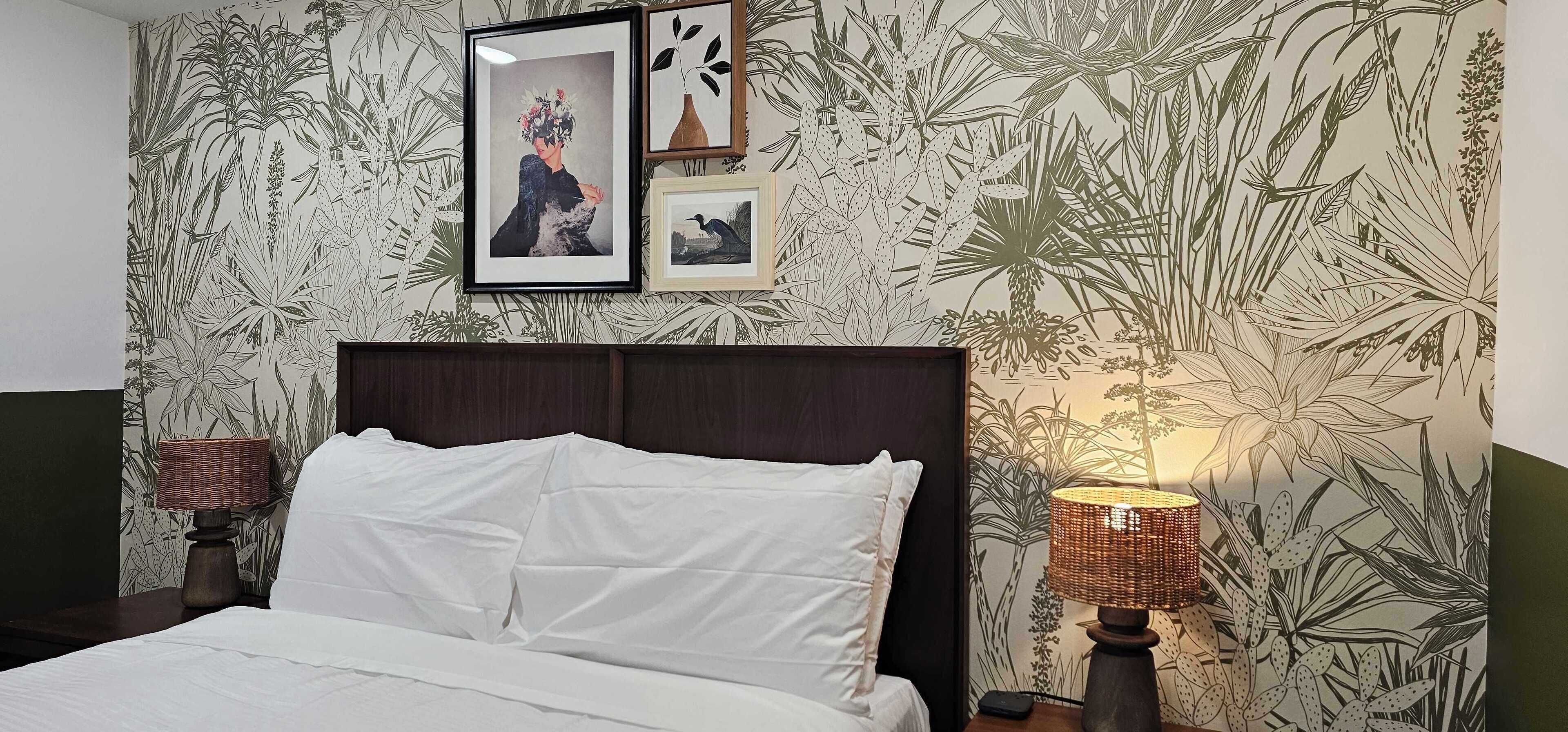 Ein Schlafzimmer mit einem Bett, einem Nachttisch, einer Lampe und gerahmten Bildern an der Wand.