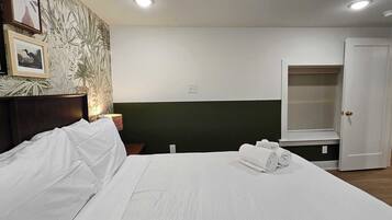 A hotel room with a bed, a nightstand, a lamp, a wardrobe, and a door.