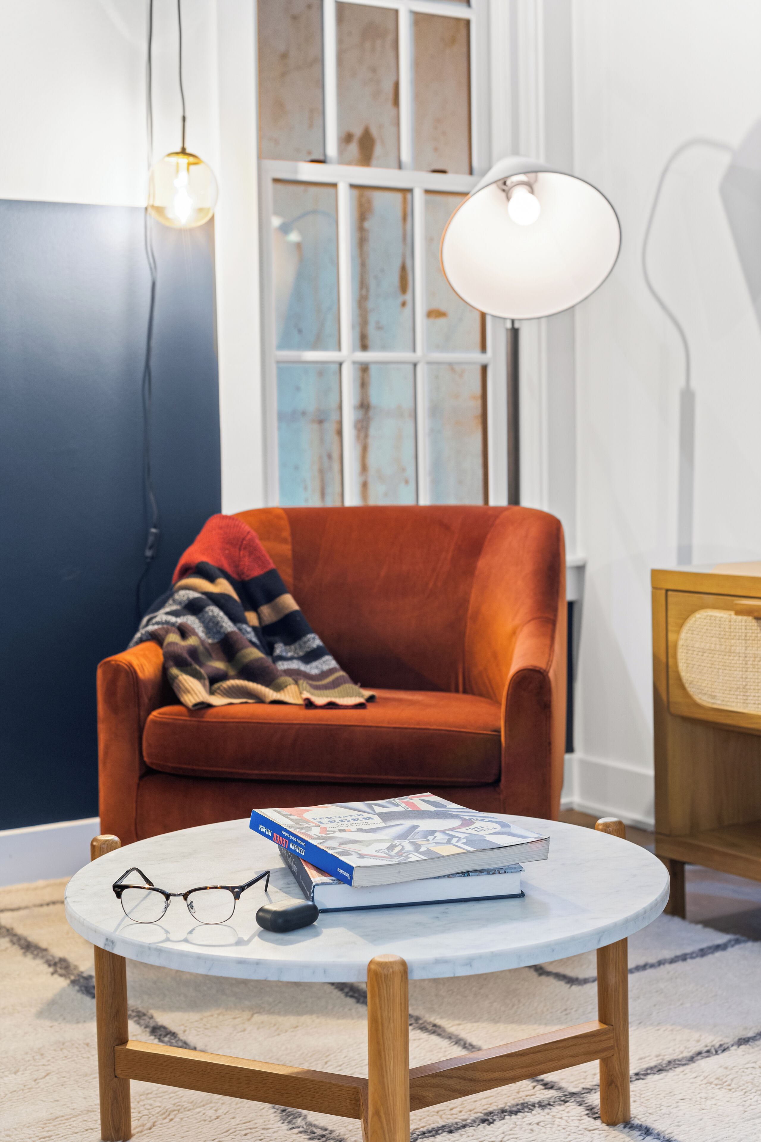 A room with a round wooden table, a pair of glasses, and a book on it.